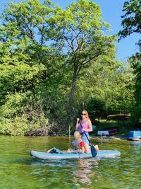 Women and woman in boat on lake against trees