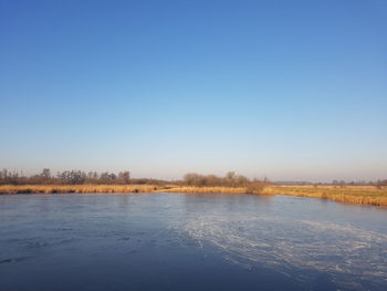 Scenic view of lake against clear blue sky