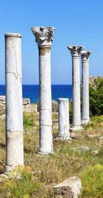 Wooden posts in sea against clear blue sky