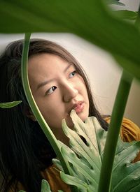 Portrait of long haired asian woman framed by philodendron leaves.