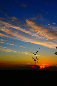 Silhouette wind turbines on field against sky during sunset