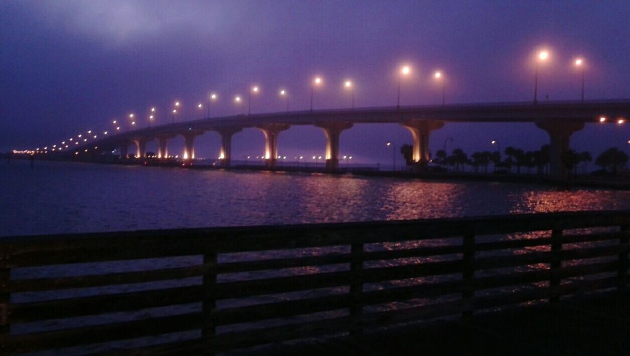 ILLUMINATED BRIDGE OVER RIVER AGAINST SKY