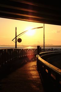 Bridge over road against sky during sunset