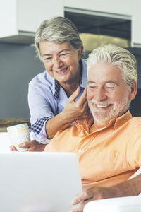 Portrait of senior woman using laptop while sitting on sofa at home