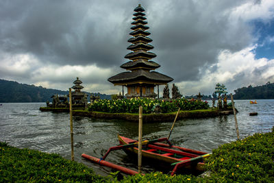 Traditional temple by lake against sky