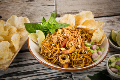 Close-up of prawns noodles with chips served in plate at wooden table