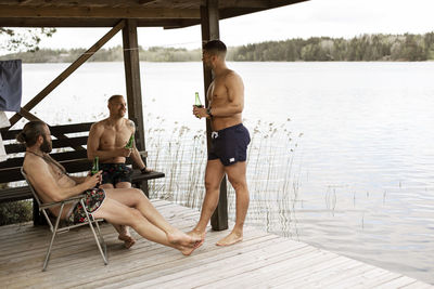 Male friends having beer at lake