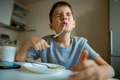 Boy, child eating macaroni, retraction long pasta into his mouth
