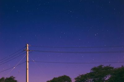 Low angle view of electricity pylon against blue sky