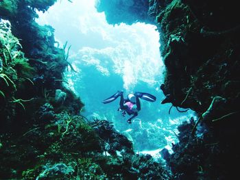 Man scuba diving in cave undersea