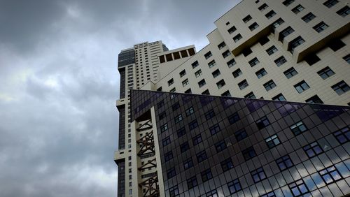 Low angle view of skyscrapers against cloudy sky