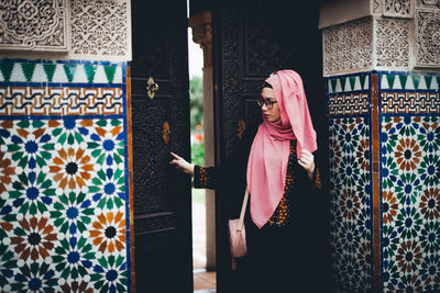 Woman standing against door at home