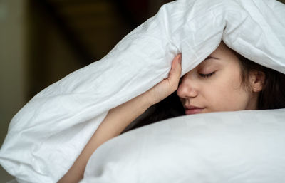 Close-up of woman covered in blanket at home