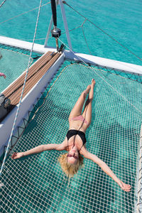 High angle view of woman lying on net over sea
