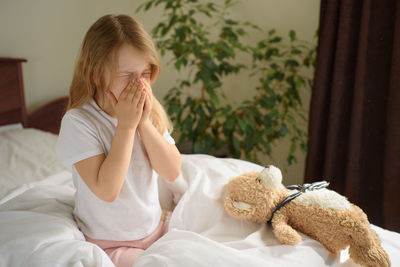 Rear view of girl sitting on bed at home