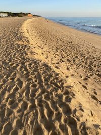 Footprints on sand at beach against sky