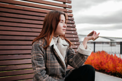 Young woman looking away while sitting at park