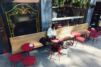 High angle view of businesswoman using smart phone at sidewalk cafe