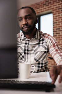 Young man using mobile phone while sitting on table