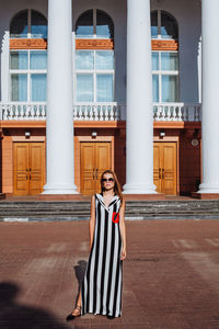 Fashionable young woman standing in city during sunny day