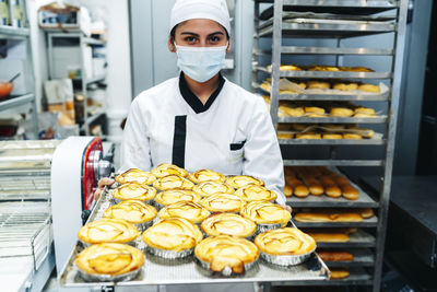 Female baker showing the freshly made cakes