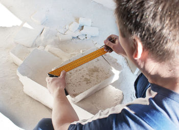 High angle view of man measuring brick on floor