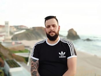 Portrait of young man standing against sea