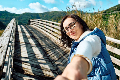 Portrait of young woman standing on boardwalk. follow me. 