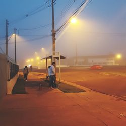 People on railroad track against sky at night