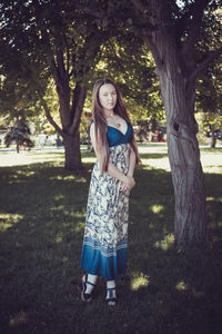 Full length portrait of young woman standing on tree trunk