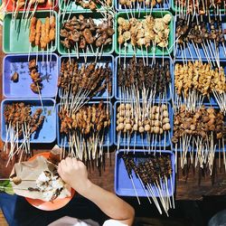 Directly above view of person eating skewer meat at market stall