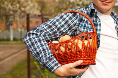 Man holding many eggs in basket. men holding whole basket of brown organic eggs on nature 