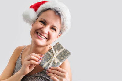 Portrait of young woman holding gift against white background