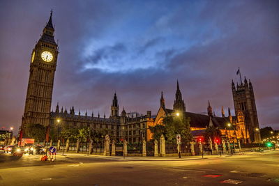 Clock tower amidst buildings in city at night