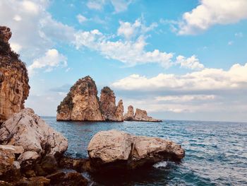 Rock formations by sea against sky