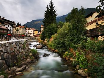 River amidst houses and buildings against sky