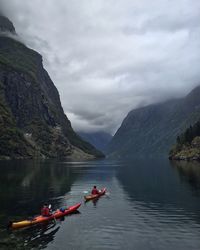 Boats in lake against cloudy sky