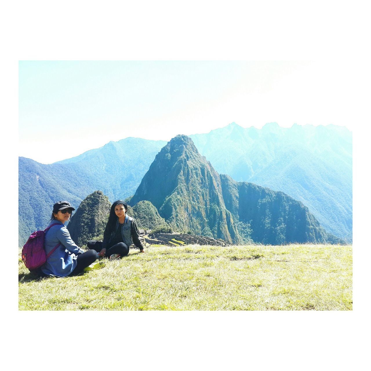 transfer print, lifestyles, leisure activity, mountain, men, auto post production filter, landscape, sitting, person, togetherness, scenics, grass, mountain range, sky, casual clothing, tranquility, field