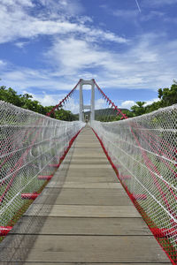 Footbridge over suspension bridge against sky