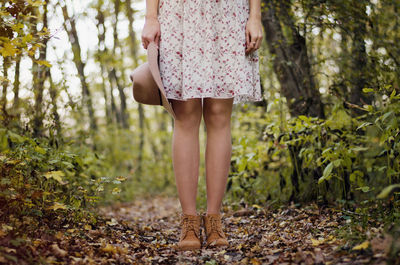 Low section of woman standing at forest