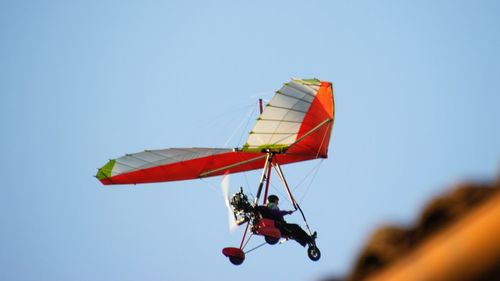 Low angle view of person hang-gliding against clear sky