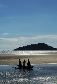 Rear view of people sitting on beach