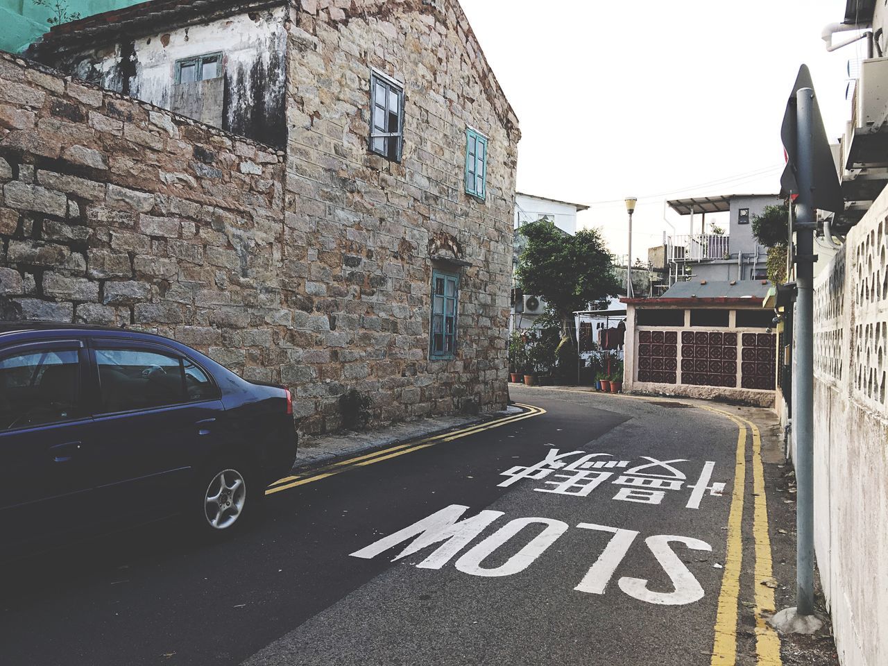 building exterior, architecture, built structure, street, transportation, road, car, land vehicle, city, building, clear sky, mode of transport, the way forward, road marking, day, outdoors, road sign, text, residential building, residential structure