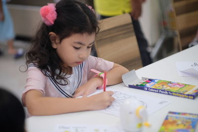 Girl drawing on book at home