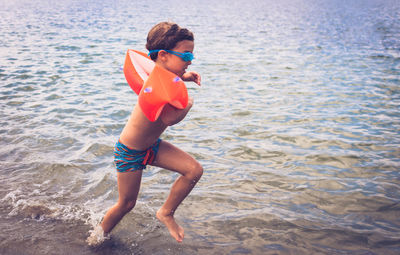 Carefree kid running through sea and having fun on summer vacation. copy space.
