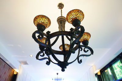 Low angle view of illuminated chandelier hanging on ceiling in building