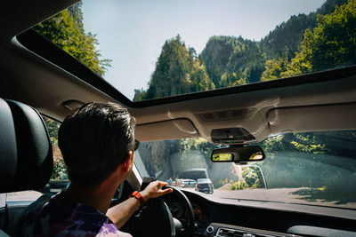 Rear view of man sitting in car on mountain road