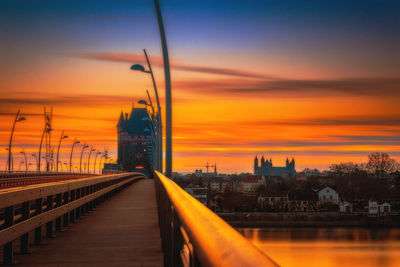 Bridge over river amidst buildings against sky during sunset