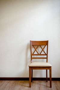 Empty chair against white wall at home