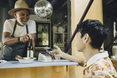 Young man doing contactless payment at counter in food truck